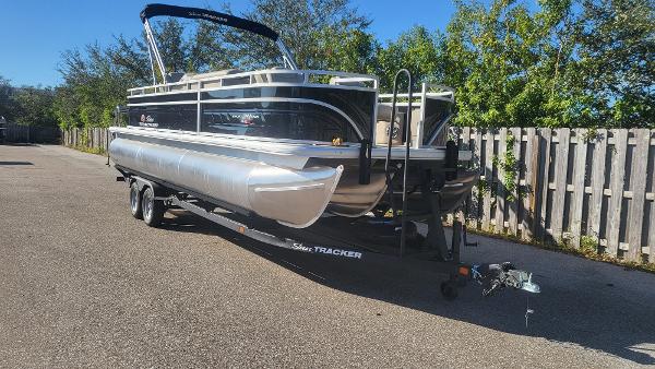 Sun Tracker Sportfish 24 XP3 2025 Sun Tracker Sportfish 24 XP3 pontoon boat on trailer, parked outdoors.