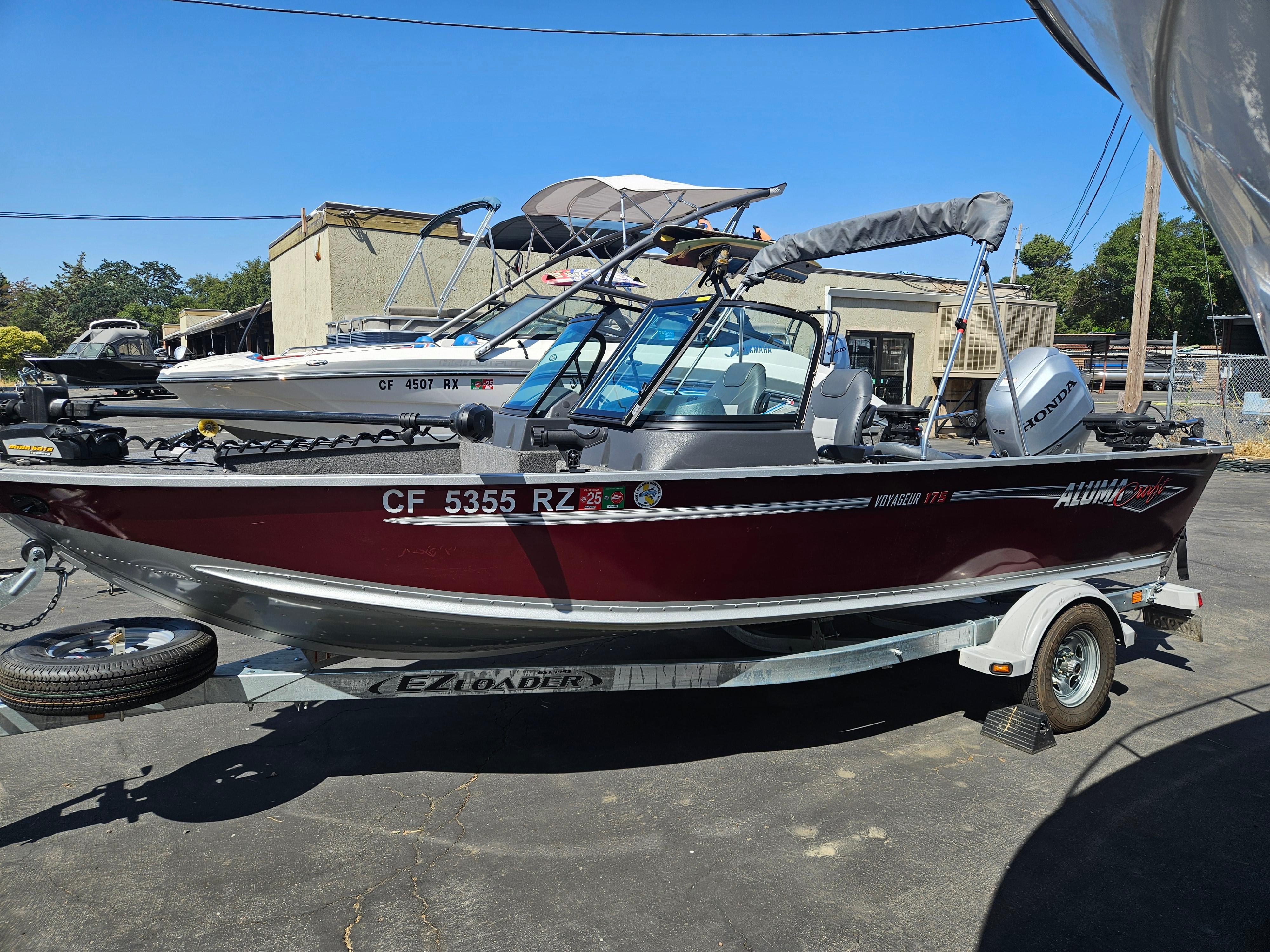 Alumacraft Voyageur 175 Sport 2018 Alumacraft Voyageur 175 Sport boat on trailer, parked outdoors under clear blue sky.