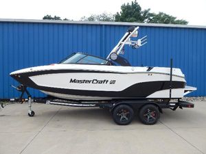 MasterCraft XT20 2023 MasterCraft XT20 boat on trailer, parked by blue building.