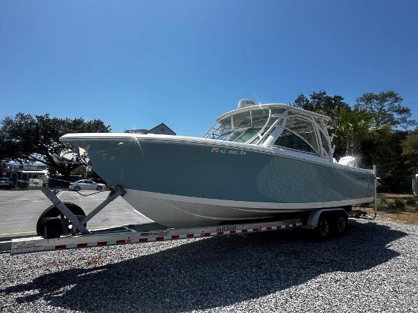 Sailfish 325DC 2018 Sailfish 325DC boat on trailer, parked on gravel under clear blue sky.
