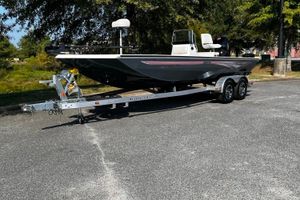 Ranger RB210 2024 Ranger RB210 boat on trailer, parked outdoors, surrounded by trees.
