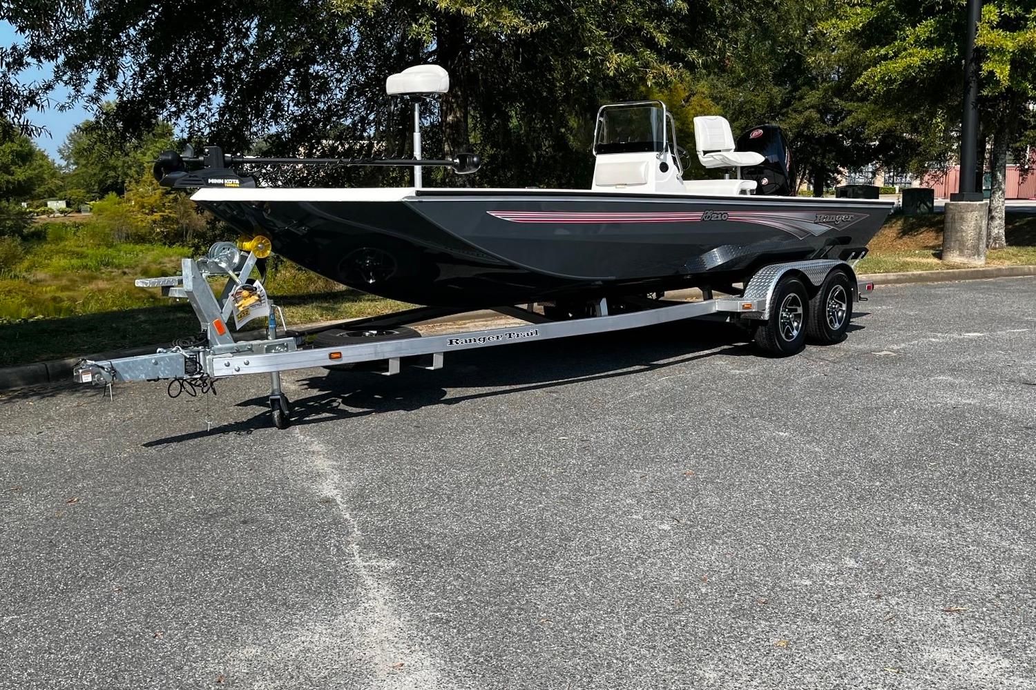 Ranger RB210 2024 Ranger RB210 boat on trailer, parked outdoors, surrounded by trees.