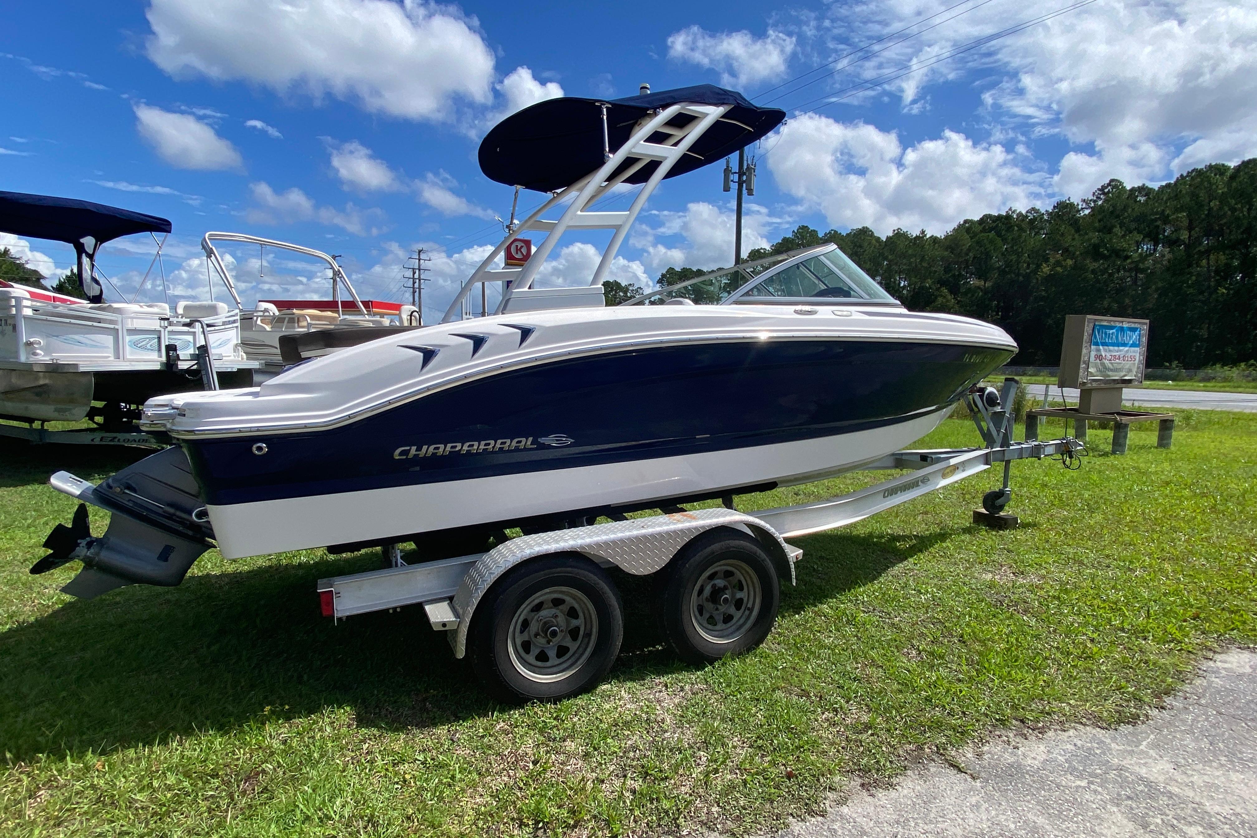 Chaparral 19 SSi 2020 Chaparral 19 SSi boat on trailer, parked on grass under a blue sky.