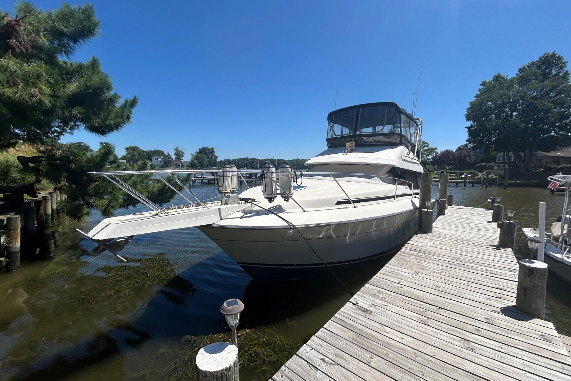 Silverton 34 Convertible 1990 Silverton 34 Convertible yacht docked by a wooden pier on a sunny day.