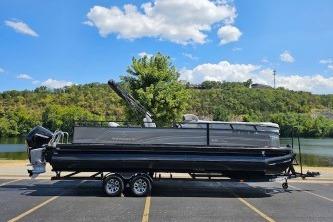 Regency 250 DL3 2024 Regency 250 DL3 pontoon boat on trailer, parked near scenic lake and greenery.