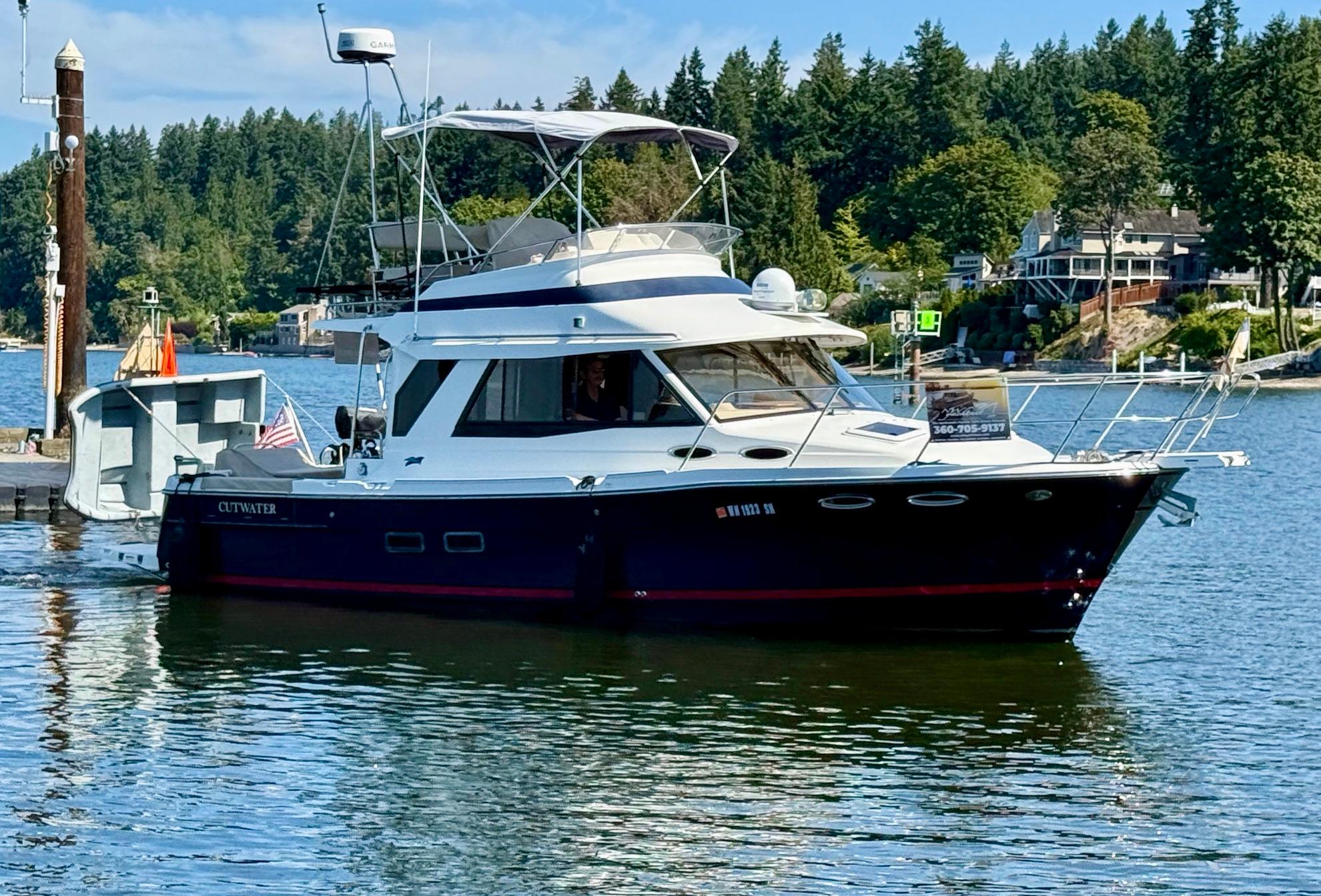 Cutwater 30CB 2015 Cutwater 30CB boat docked on a scenic lake with lush greenery.