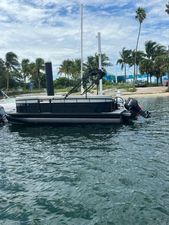 Vision Marine Technologies WX Tritoon 2024 Vision Marine Technologies WX Tritoon boat docked near palm trees.