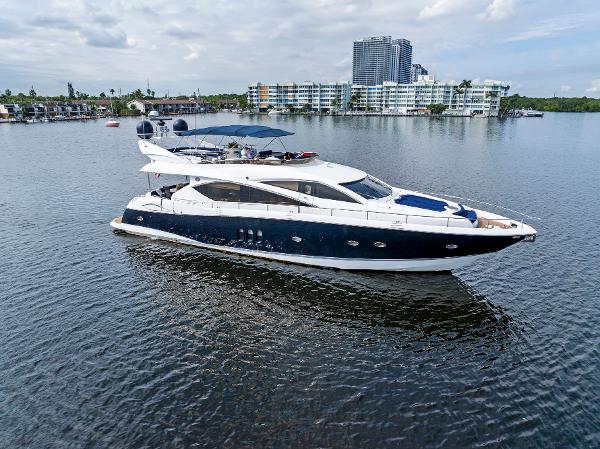 Sunseeker 75 Yacht Luxurious 2006 Sunseeker 75 Yacht cruising on calm waters near modern waterfront buildings.