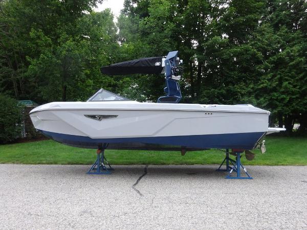 Nautique S23 2023 Nautique S23 boat on stands, side view, white and blue hull.