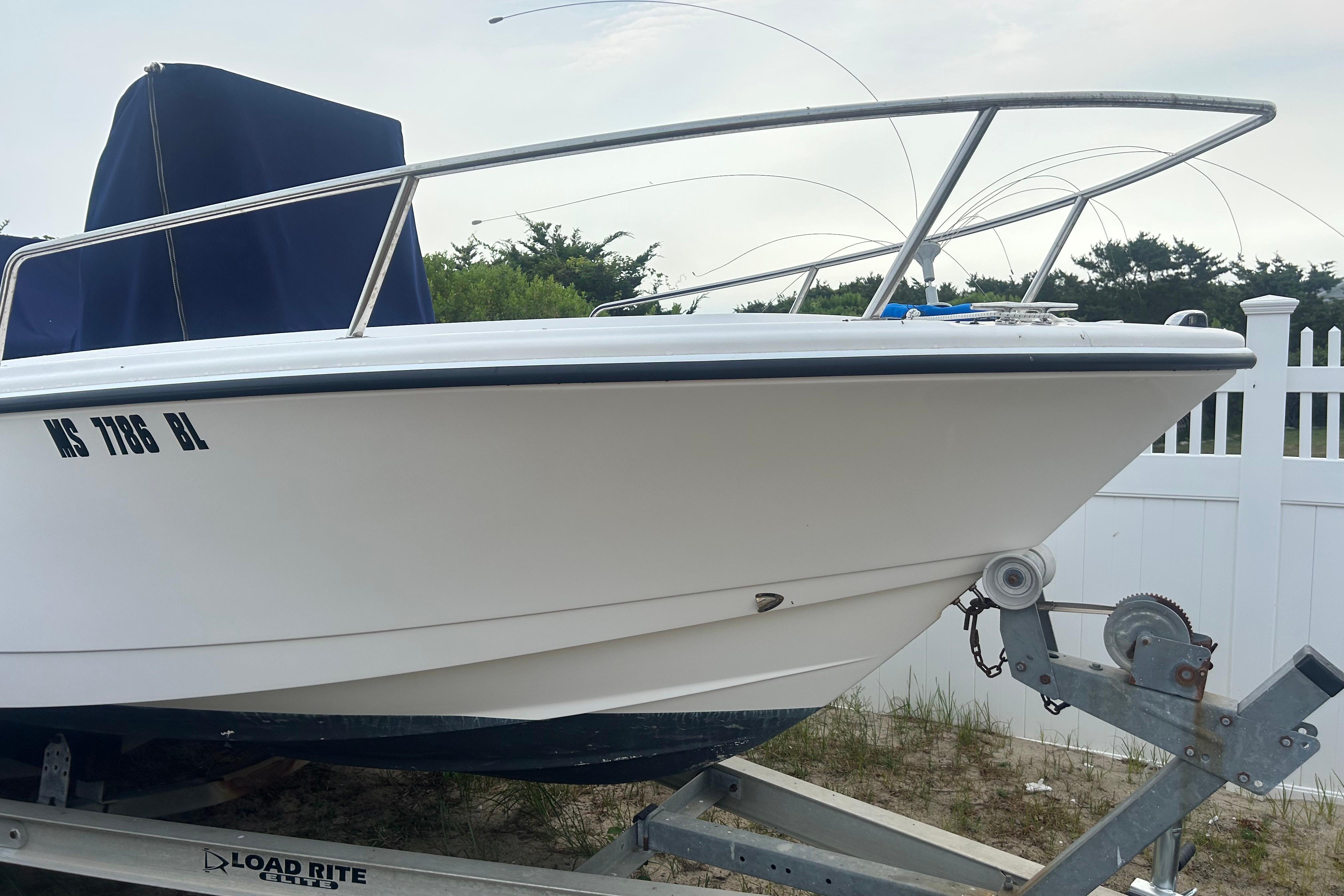 Edgewater 18 2013 Edgewater 18 boat on trailer, white hull, parked near white fence.
