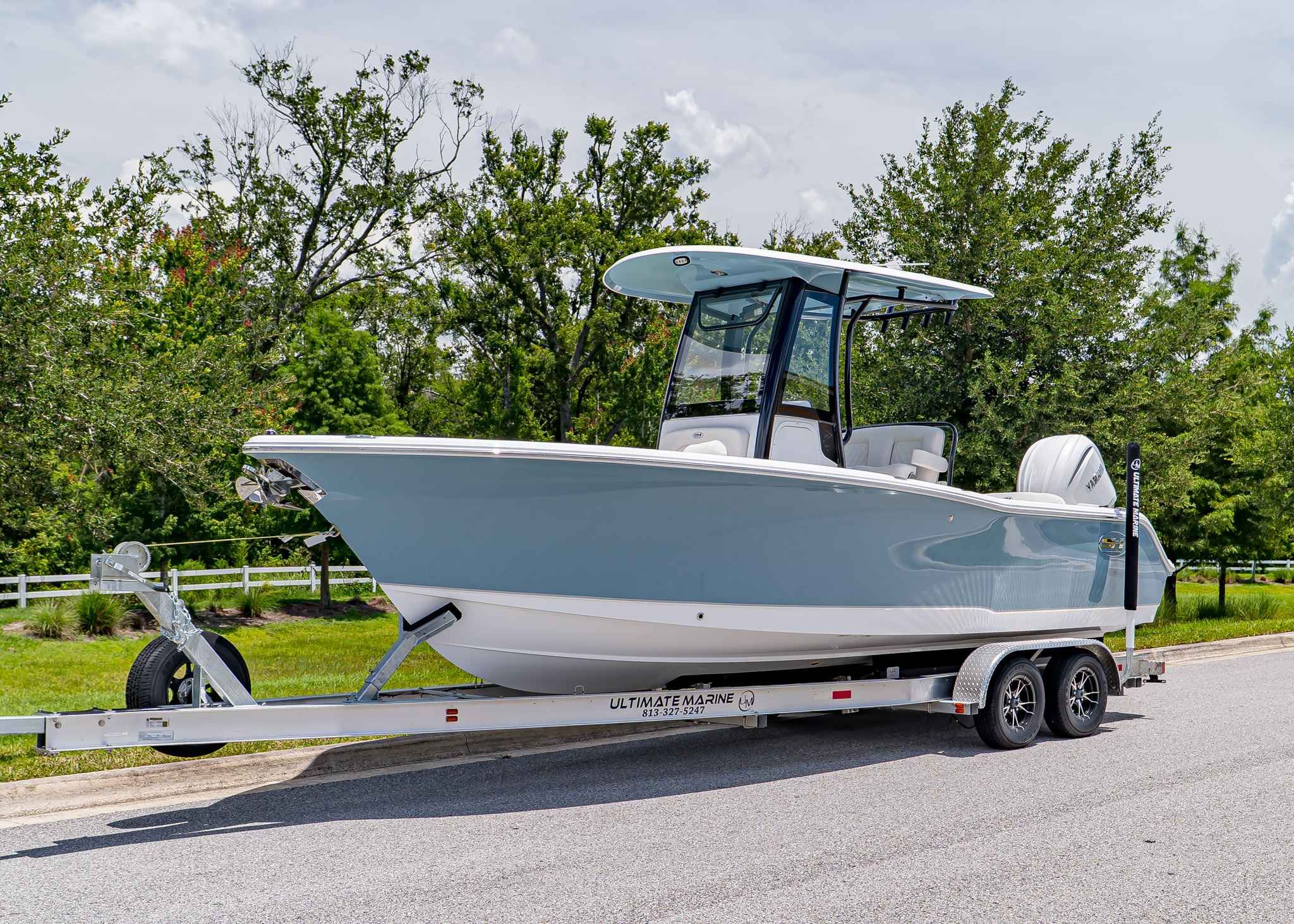 Sea Hunt Ultra 245 SE 2026 Sea Hunt Ultra 245 SE boat on trailer, parked on a road with trees in background.
