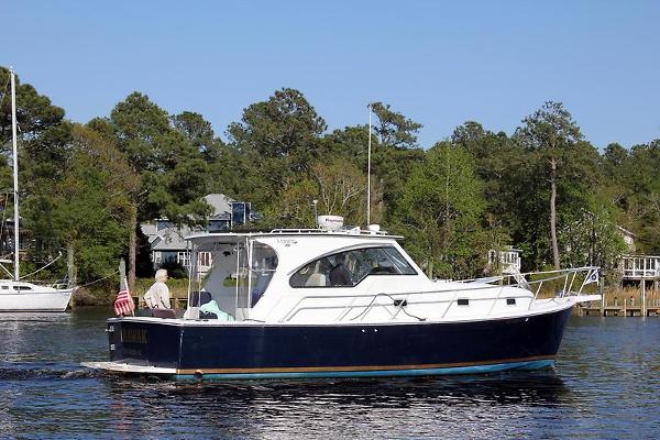 Mainship Pilot 34 Sedan 2001 Mainship Pilot 34 Sedan cruising on a calm river with trees in the background.