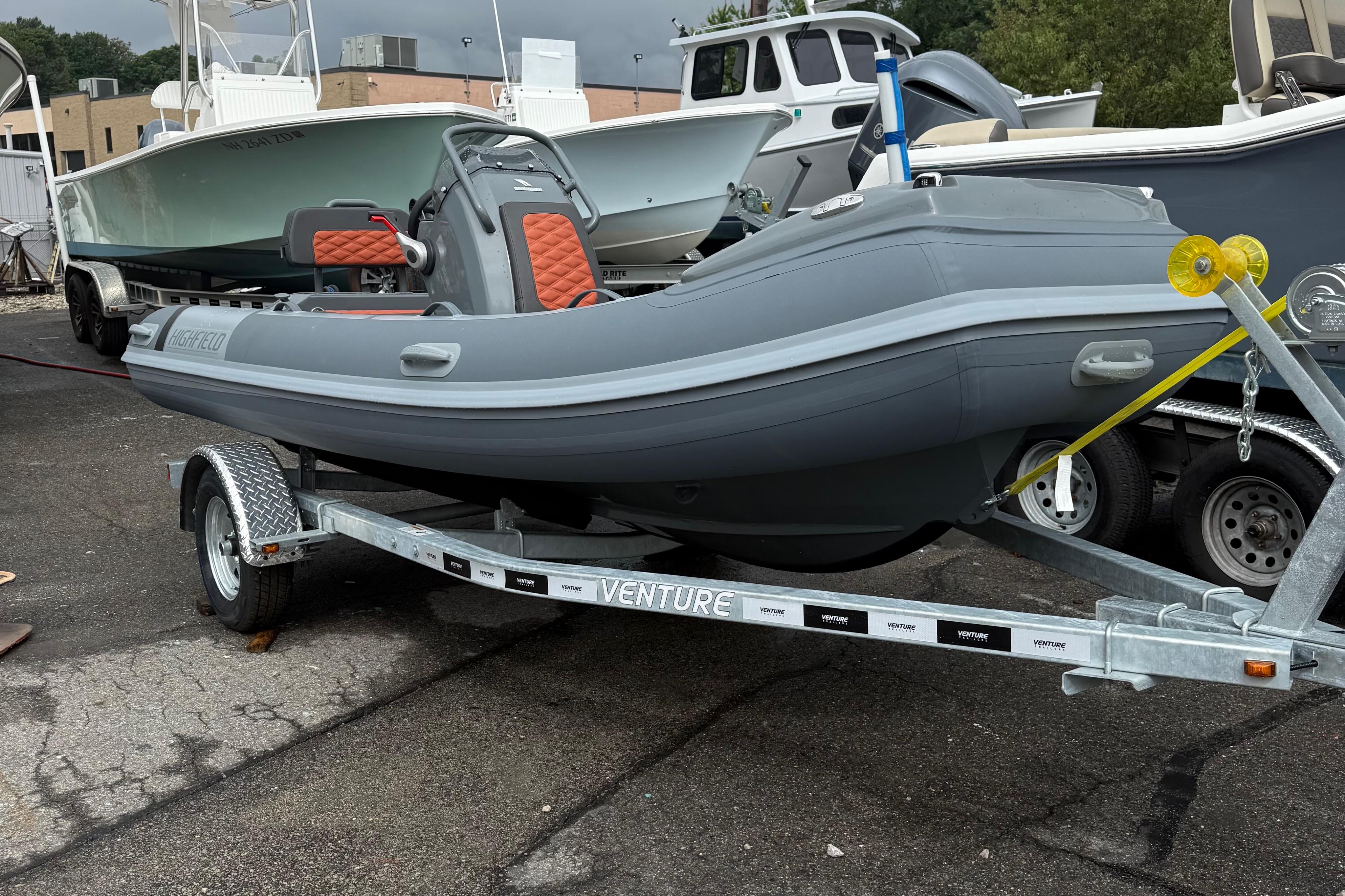 Highfield Sport 420 2025 Highfield Sport 420 boat on trailer, gray with orange seats, parked outdoors.
