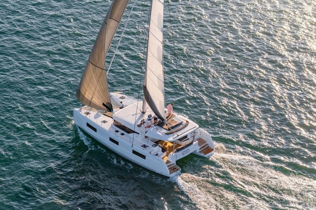 Lagoon 46 2023 Lagoon 46 catamaran sailing on open water, aerial view.