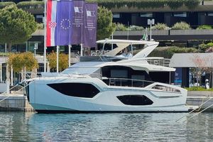 Absolute 56 FLY Luxury Absolute 56 FLY yacht docked, 2025 model, with flags and modern architecture in the background.