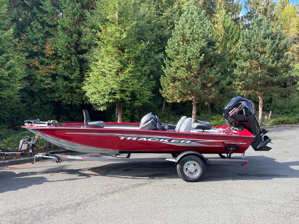 Tracker Pro Team 190 TX 2023 Tracker Pro Team 190 TX boat on trailer, parked near lush green trees.
