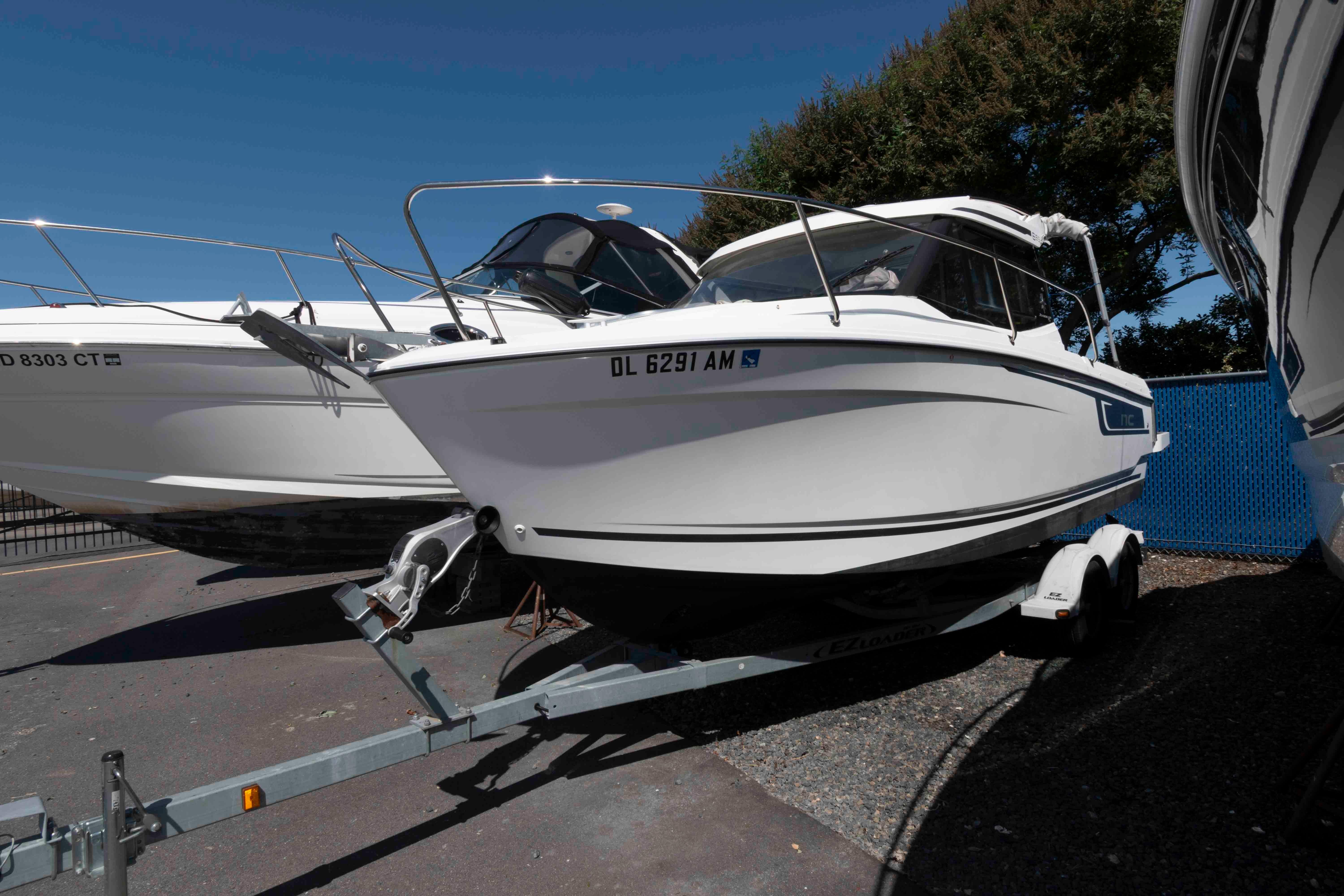Jeanneau NC 695 2020 Jeanneau NC 695 boat on trailer, parked outdoors under clear blue sky.