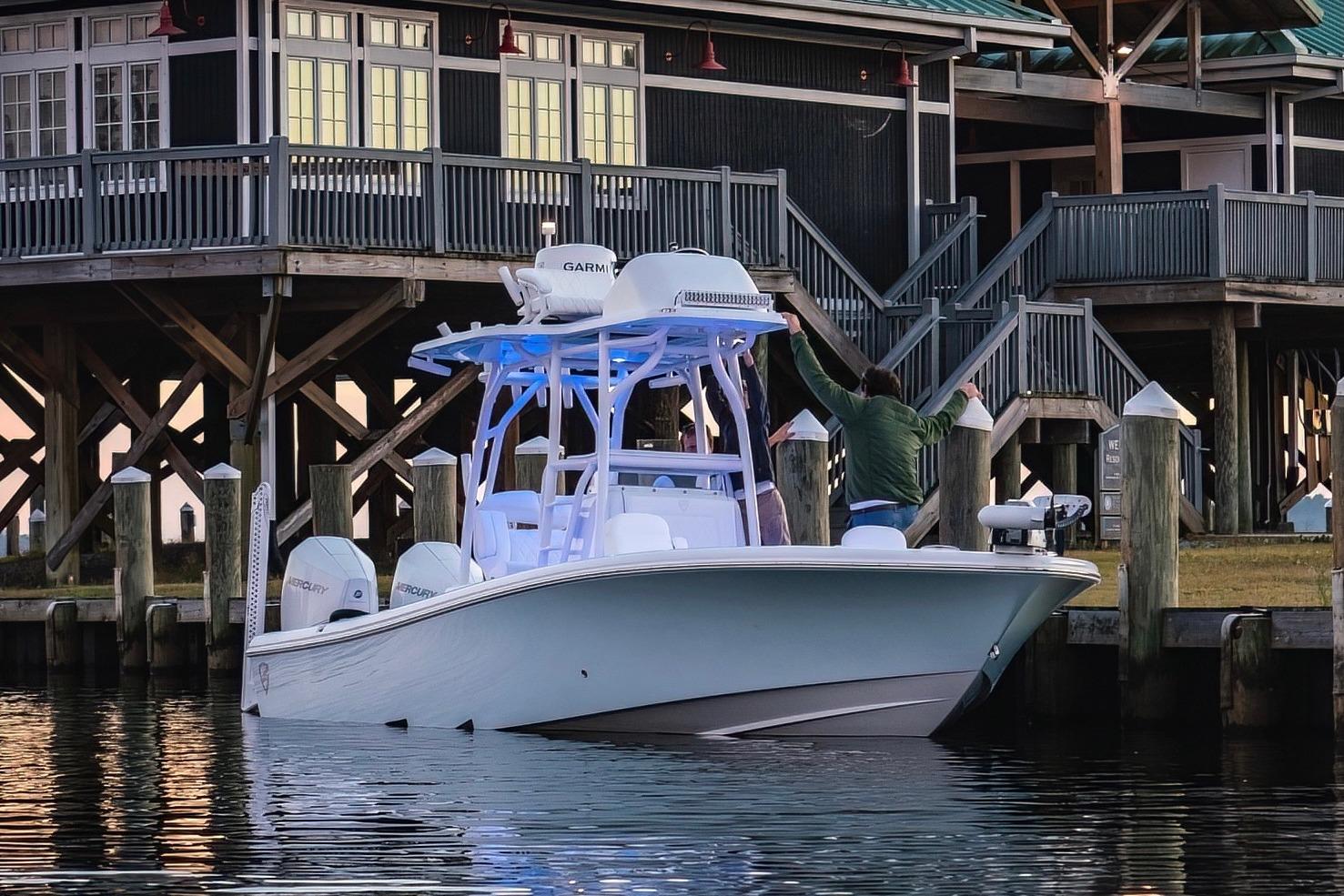 Barker Boatworks 26 Open 2022 Barker Boatworks 26 Open docked near a wooden building, featuring dual Mercury engines.