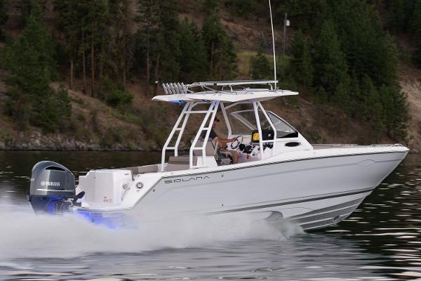Solara S-250 CW 2023 Solara S-250 CW boat cruising on a lake with forested shoreline.