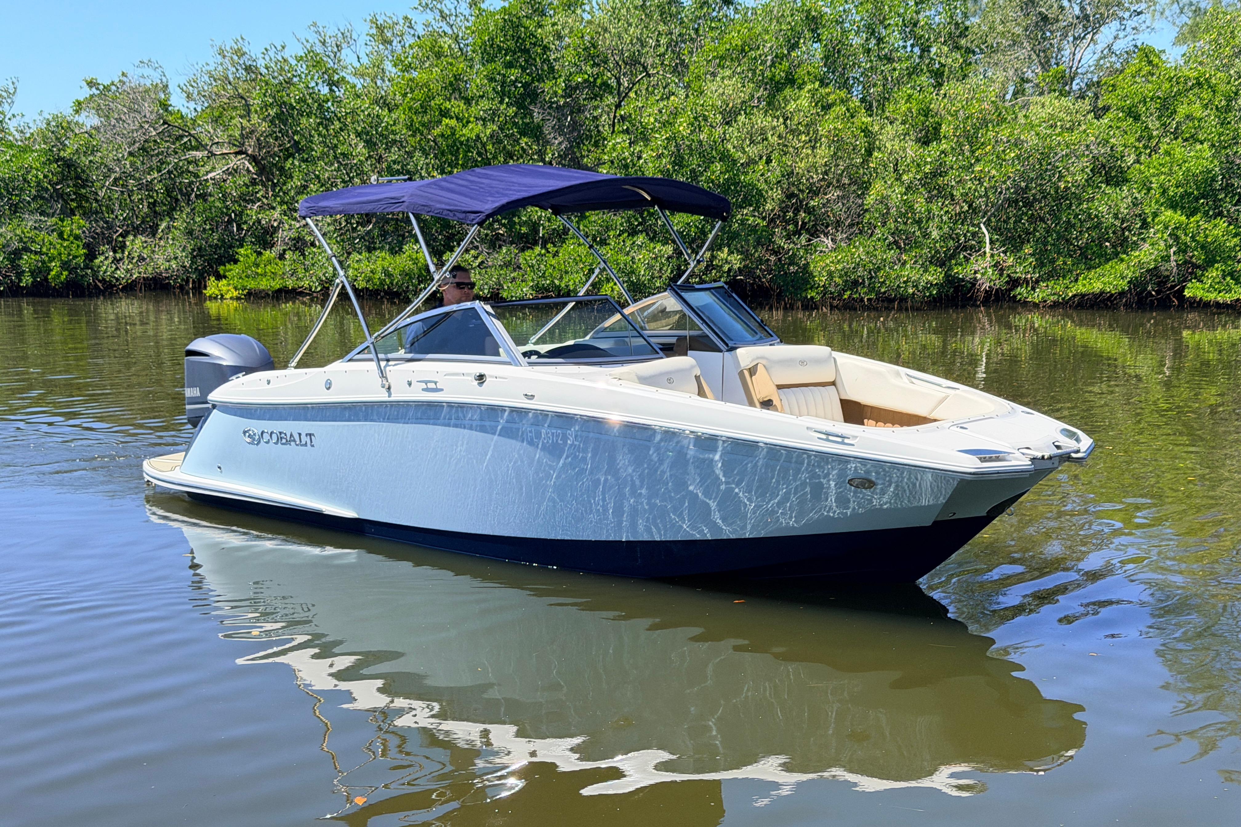 Cobalt 23SC 2018 Cobalt 23SC boat on calm water, surrounded by lush greenery.