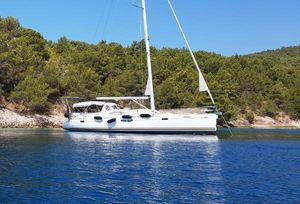 Jeanneau Sun Odyssey 54 DS 2009 Jeanneau Sun Odyssey 54 DS sailboat anchored near a forested shoreline.