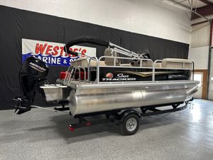 Sun Tracker Party Barge 16 DLX 2025 Sun Tracker Party Barge 16 DLX pontoon boat on trailer in showroom.