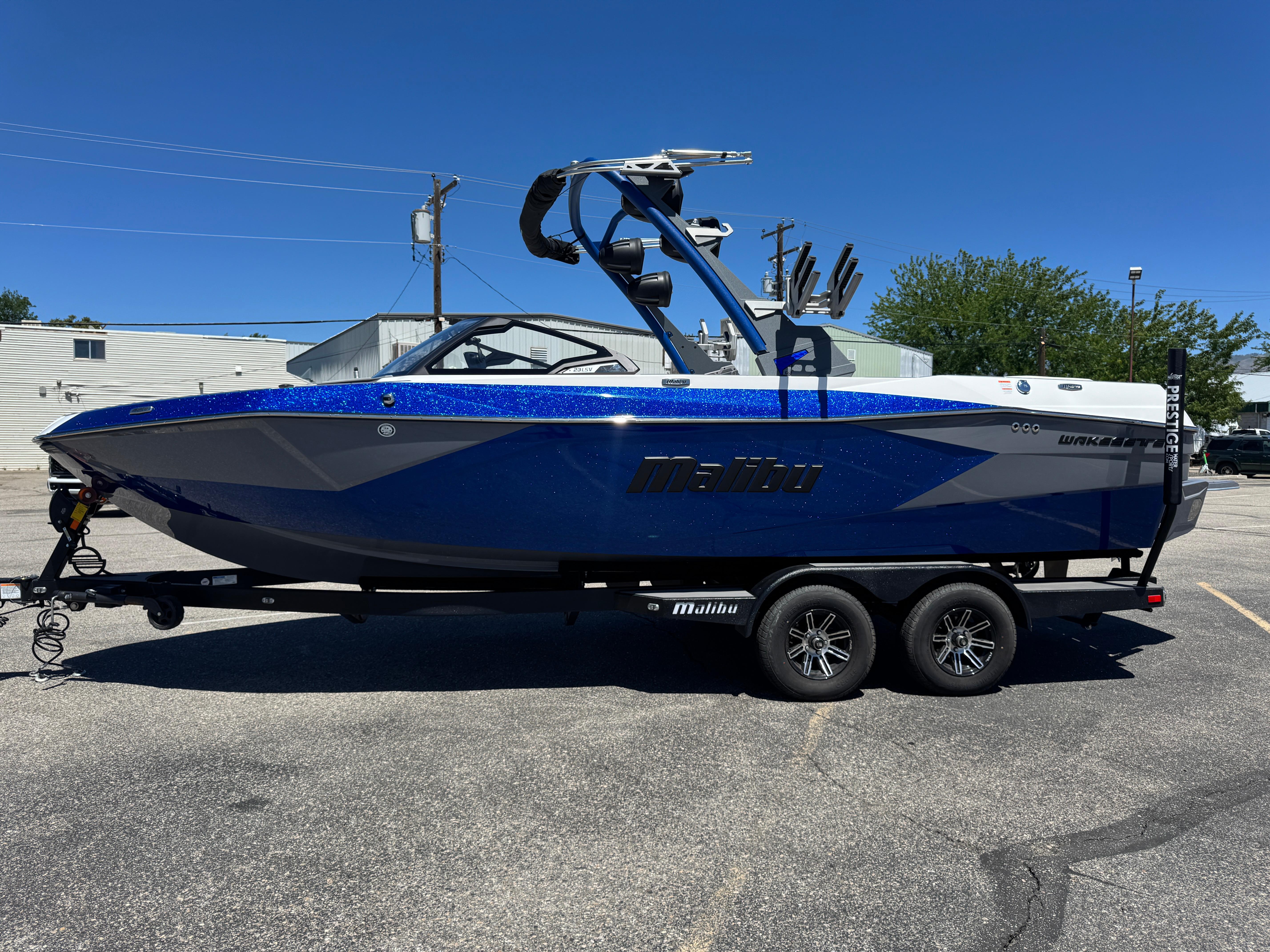 Malibu Wakesetter 23 LSV 2024 Malibu Wakesetter 23 LSV boat on trailer, blue and gray design, parked outdoors.
