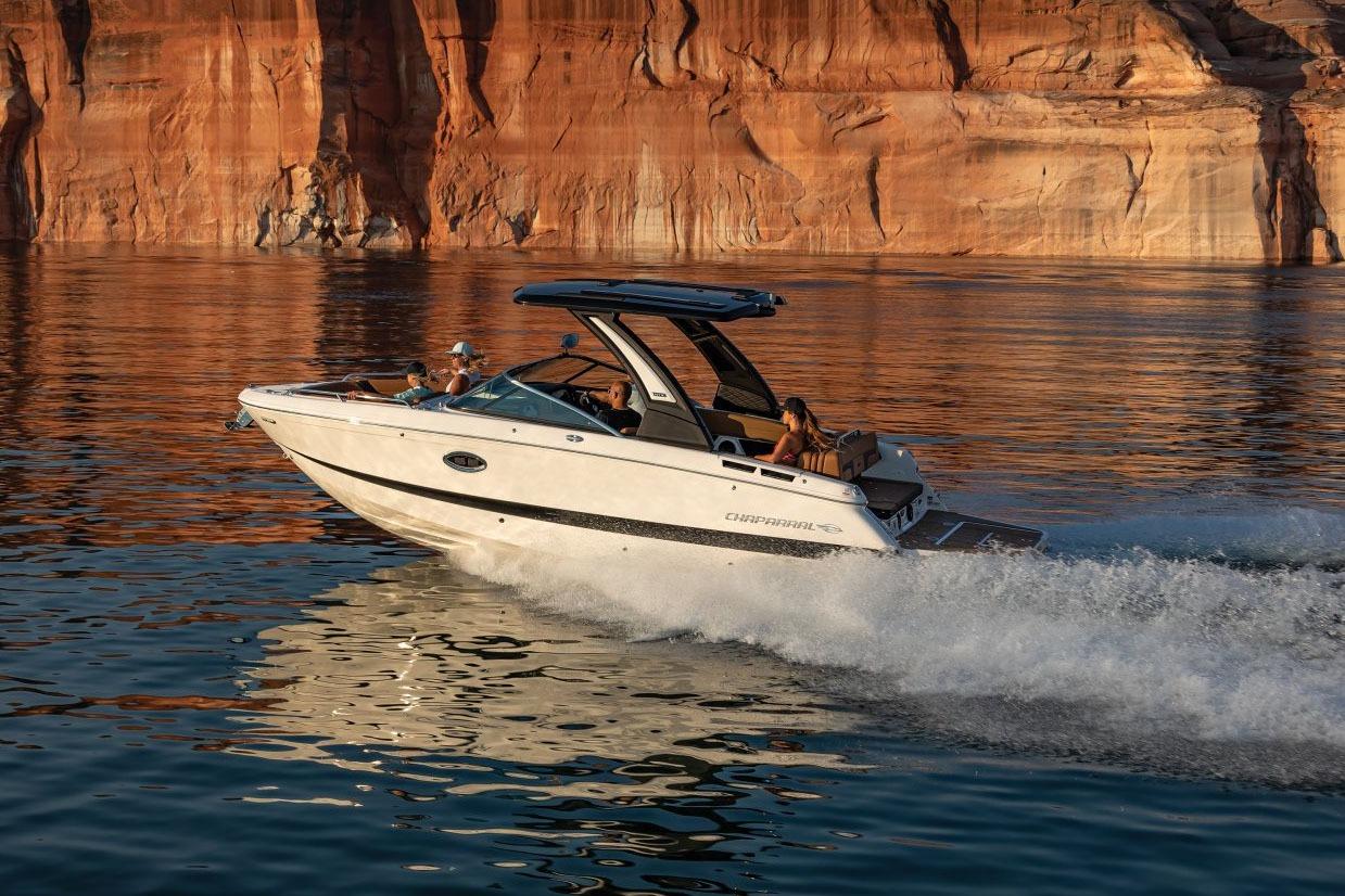 Chaparral 26 Surf 2025 Chaparral 26 Surf boat cruising on a scenic lake with rocky cliffs.