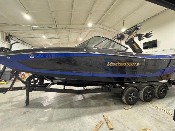 MasterCraft X26 2024 MasterCraft X26 boat in a garage, featuring a sleek black and blue design.