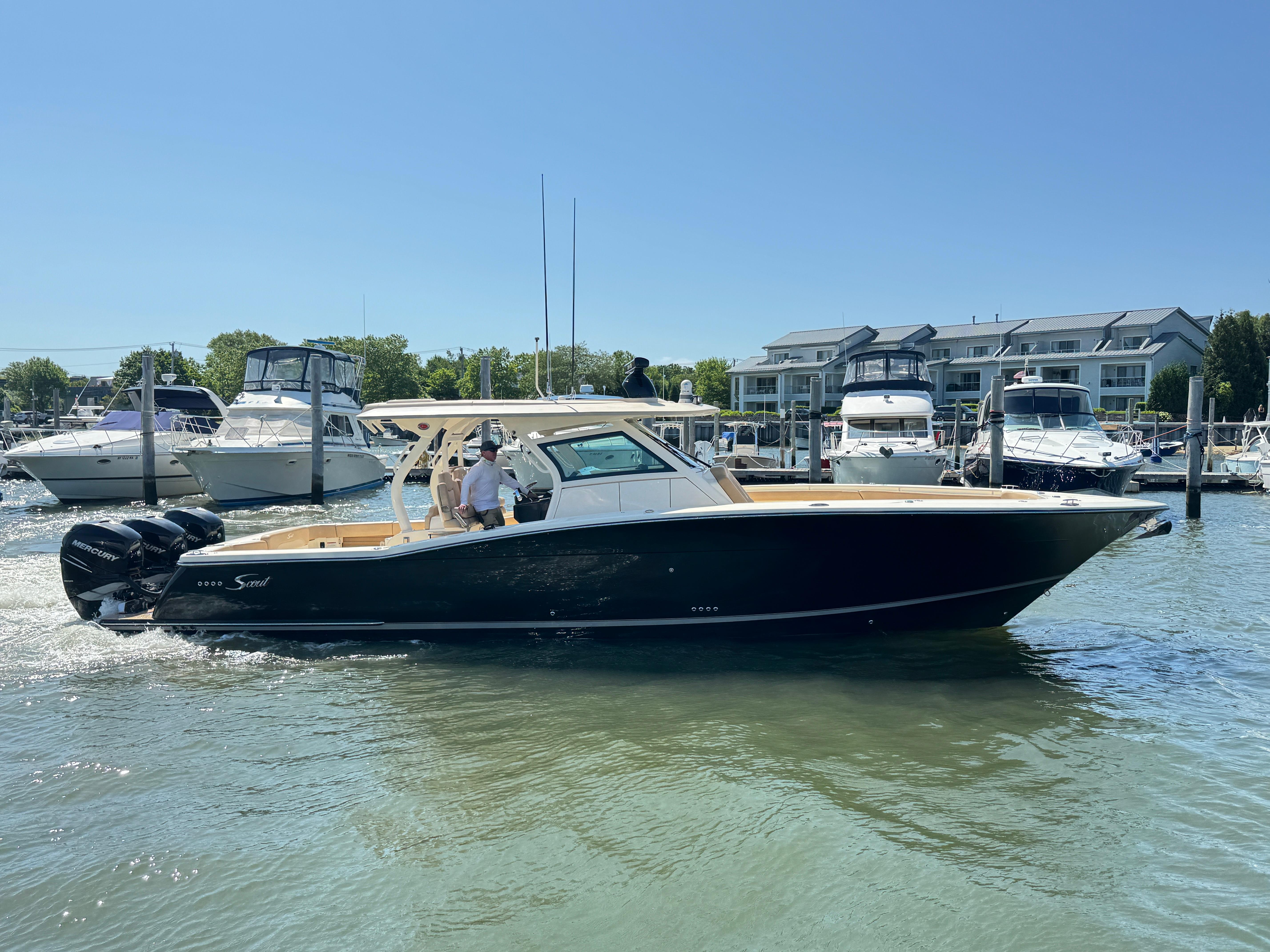 Scout 380 LXF 2018 Scout 380 LXF boat cruising in a marina with other boats docked nearby.
