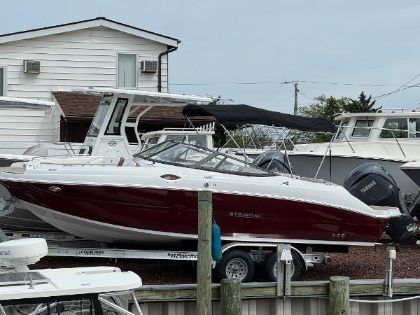 Stingray 231 DC 2025 Stingray 231 DC boat with red hull on trailer at marina.