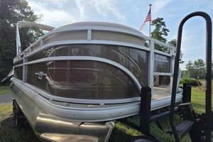 Sun Tracker SportFish 20 DLX 2025 Sun Tracker Sportfish™ 20 DLX pontoon boat on trailer, American flag in background.