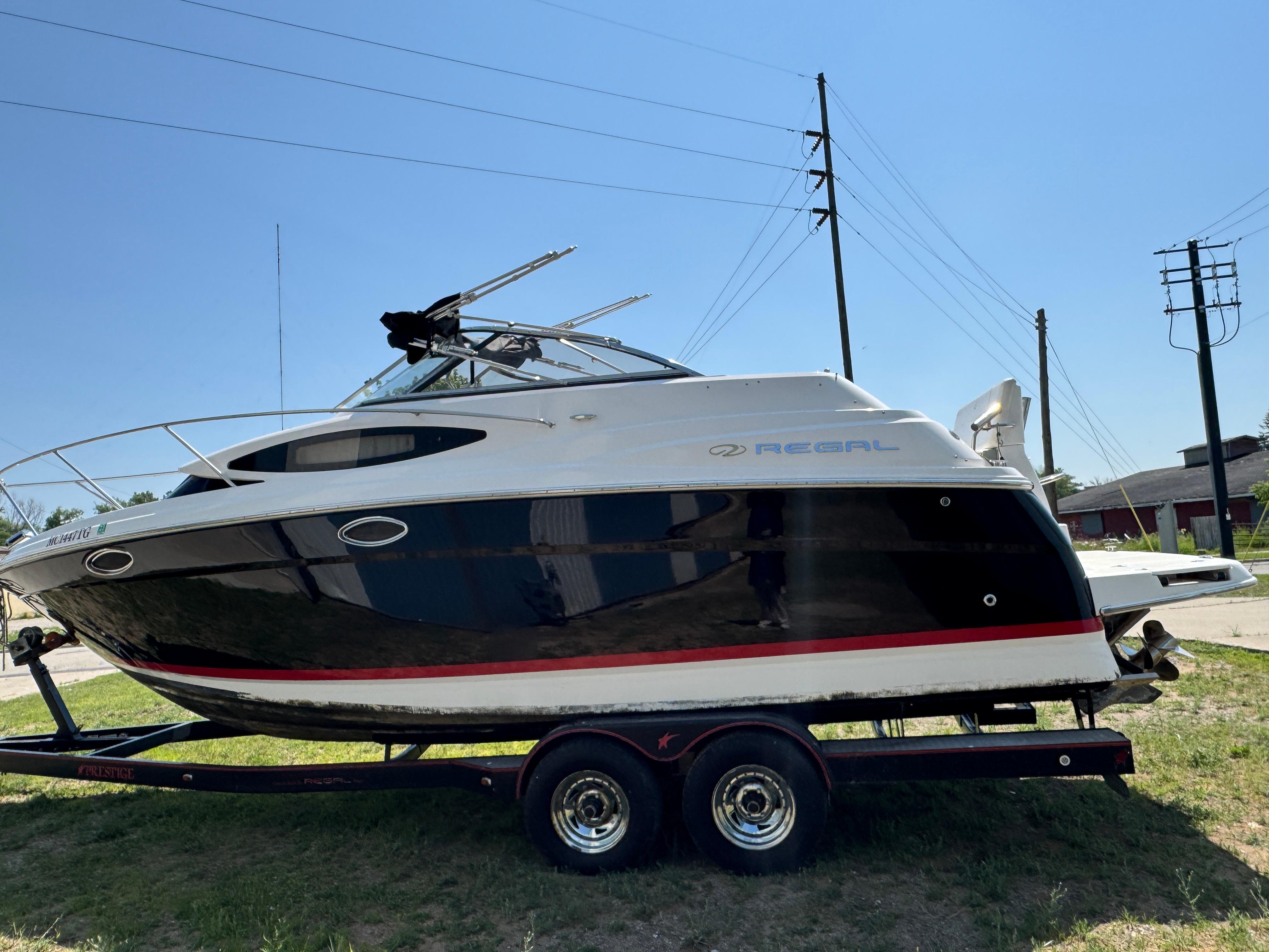 Regal 2565 Window Express 2006 Regal 2565 Window Express boat on trailer, parked outdoors under clear sky.