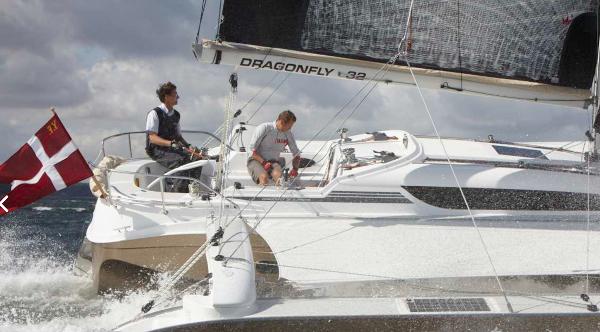 Dragonfly 32 Sailing on Dragonfly 32 trimaran, two people navigate choppy waters under cloudy skies.