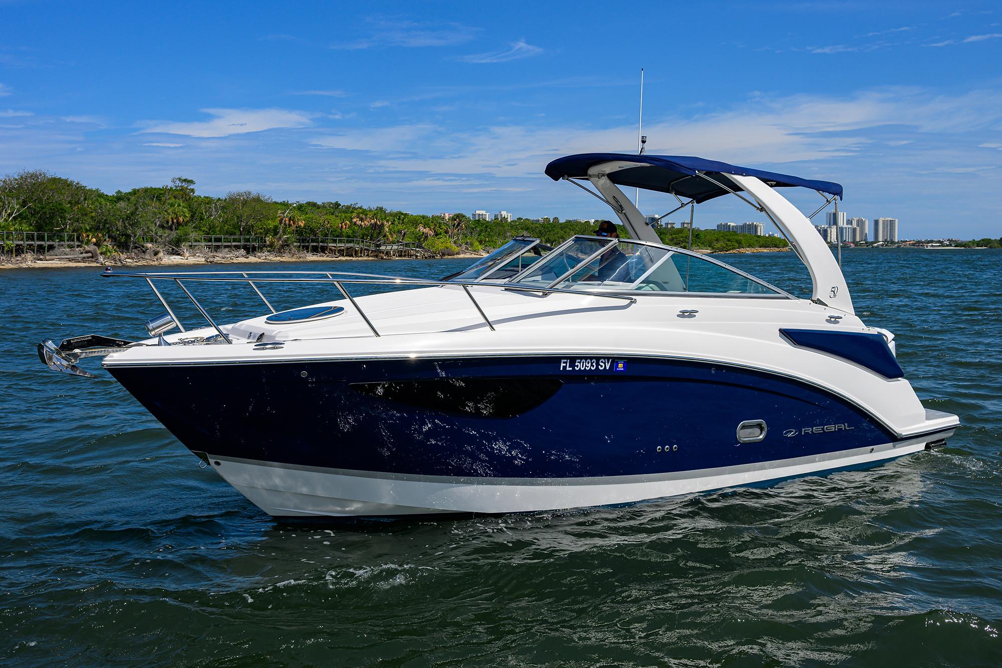 Regal 26 XO 2021 Regal 26 XO boat cruising on a sunny day with blue skies and lush shoreline.