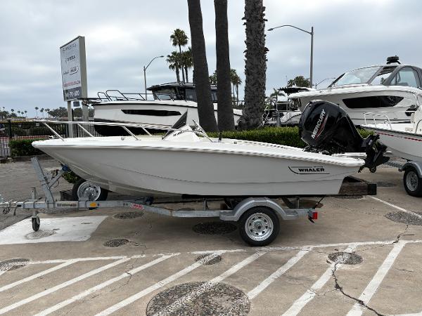 Boston Whaler 130 Super Sport 2025 Boston Whaler 130 Super Sport boat on trailer, parked outdoors near palm trees.