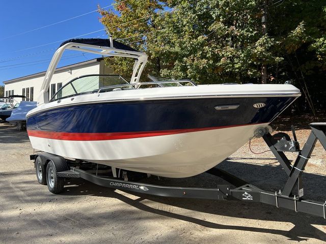 Chaparral 247 SSX 2025 Chaparral 247 SSX boat on trailer, blue and white with red stripe, parked outdoors.