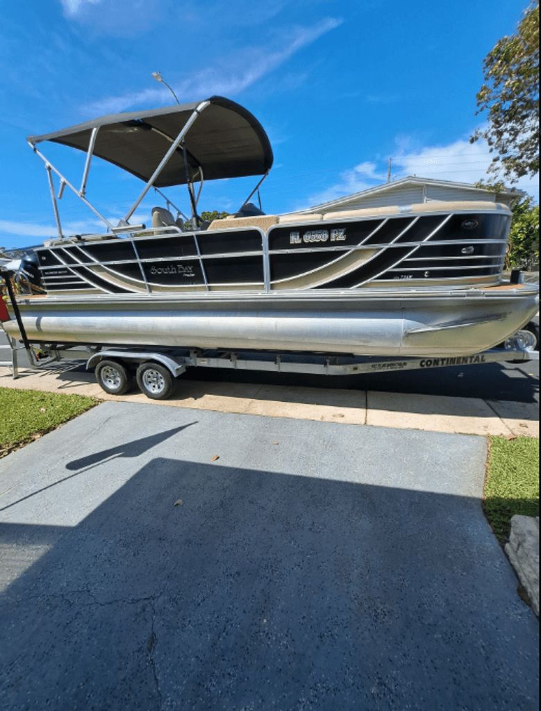 South Bay 525 CR 2013 South Bay 525 CR pontoon boat on trailer, parked in driveway under clear blue sky.
