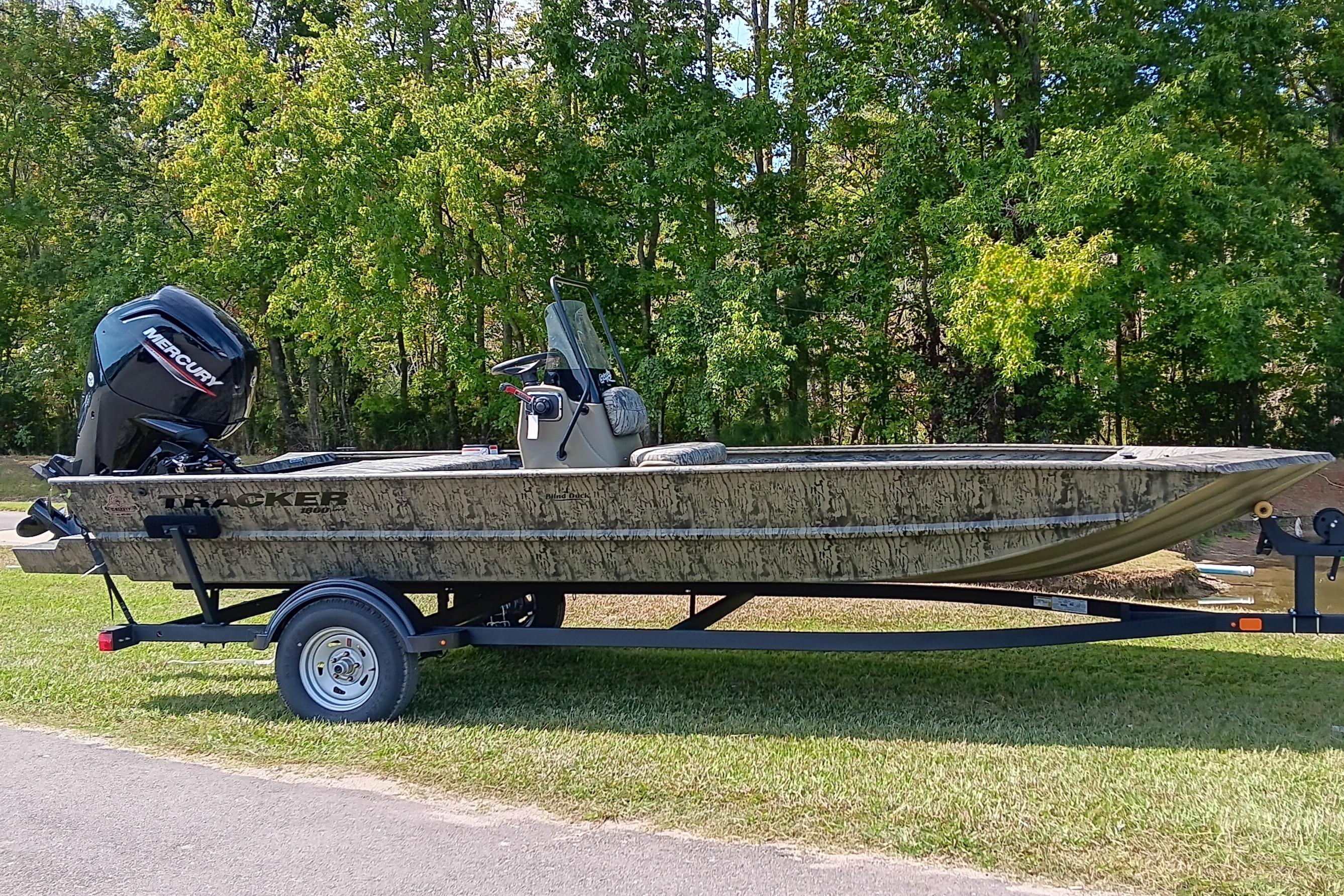 Tracker Grizzly 1860 CC 2026 Tracker Grizzly 1860 CC boat on trailer, parked on grass with trees in background.