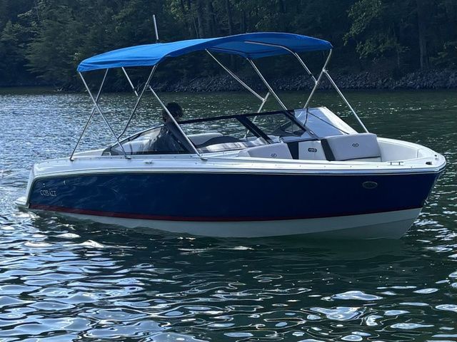 Cobalt CS22 2024 Cobalt CS22 boat with blue canopy cruising on a serene lake.