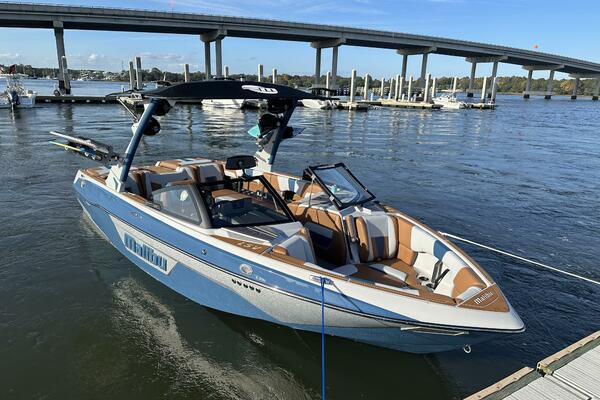 Malibu Wakesetter 23 LSV 2023 Malibu Wakesetter 23 LSV boat docked on a sunny day near a bridge.