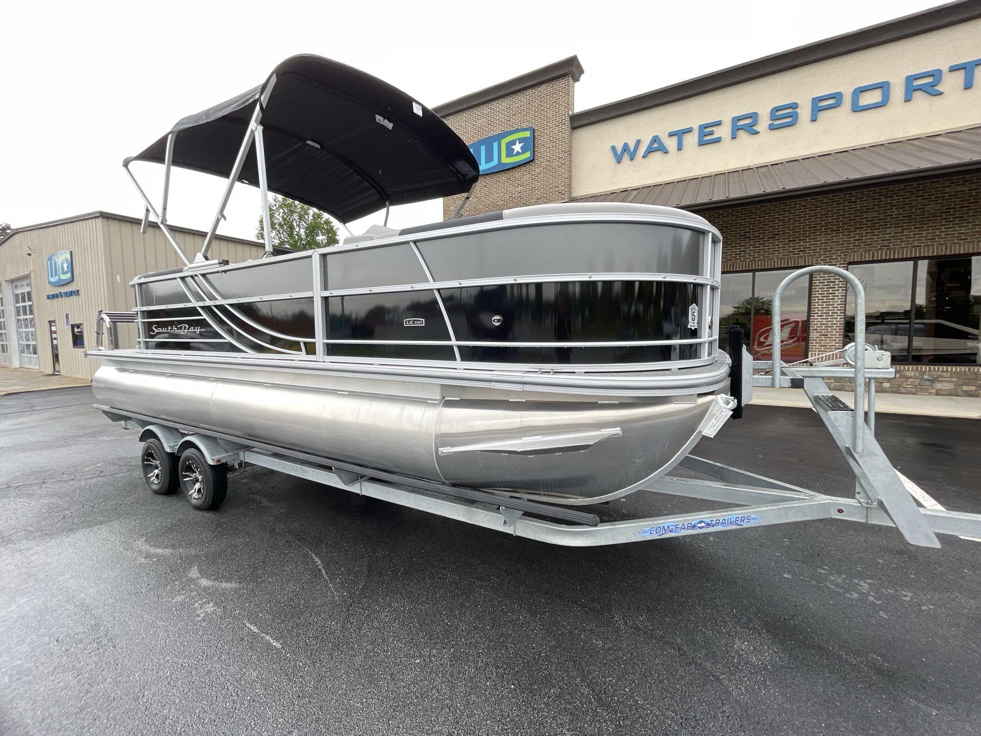 South Bay 222RSLE 2025 South Bay 222RSLE pontoon boat on trailer outside watersports store.