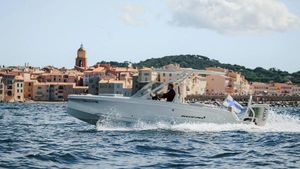 Axopar AX/E 22 T-Top 2025 Axopar AX/E 22 T-Top boat cruising near coastal town.