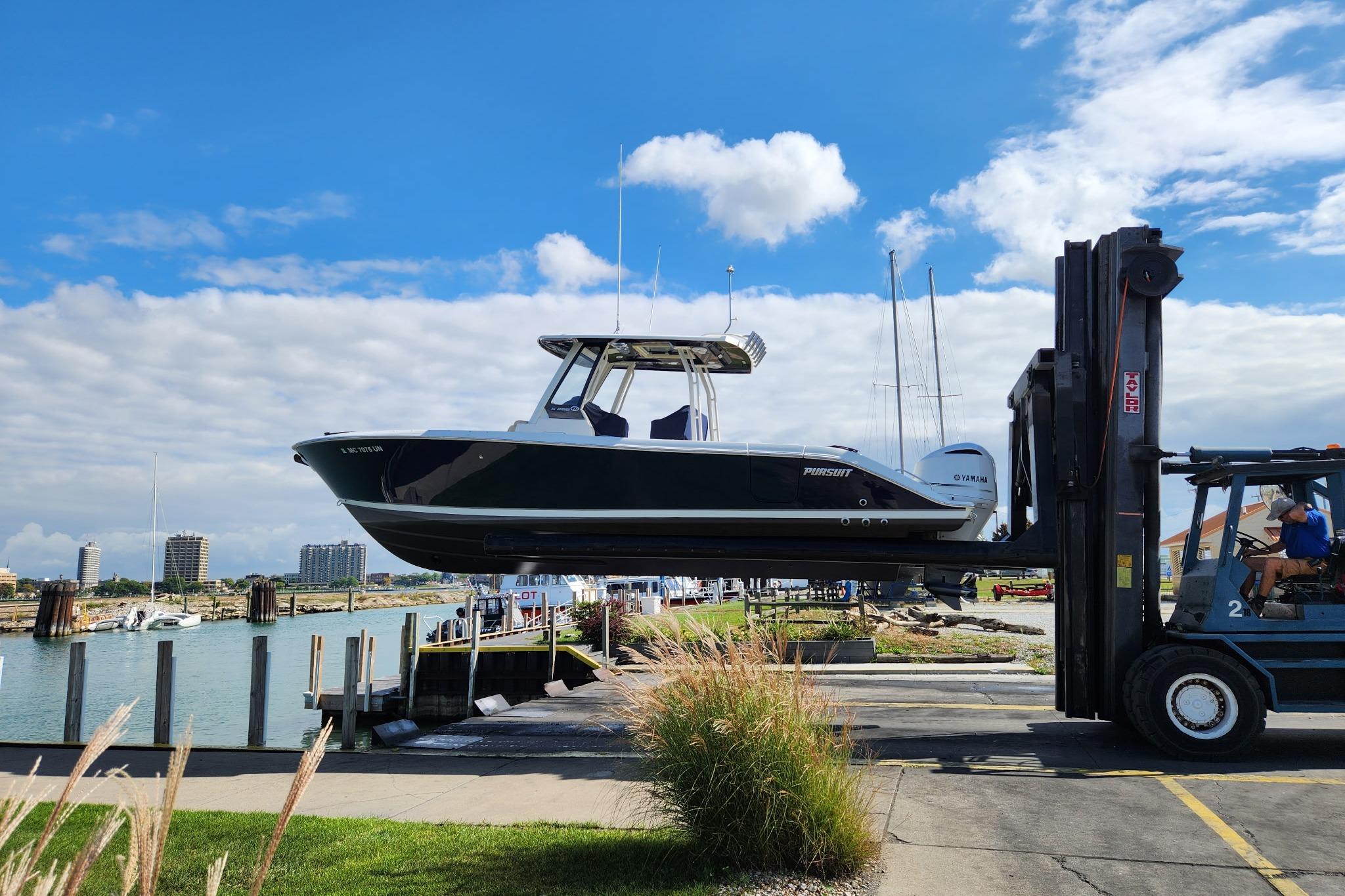 Pursuit S 288 Sport 2021 Pursuit S 288 Sport boat lifted by forklift at marina, clear sky background.