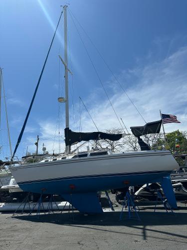 Catalina 34 1988 Catalina 34 sailboat on stands, clear sky, American flag, marina setting.