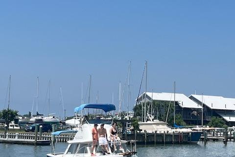 Bertram Flybridge Cruiser 1979 Bertram Flybridge Cruiser with people onboard, docked at a marina under clear blue skies.