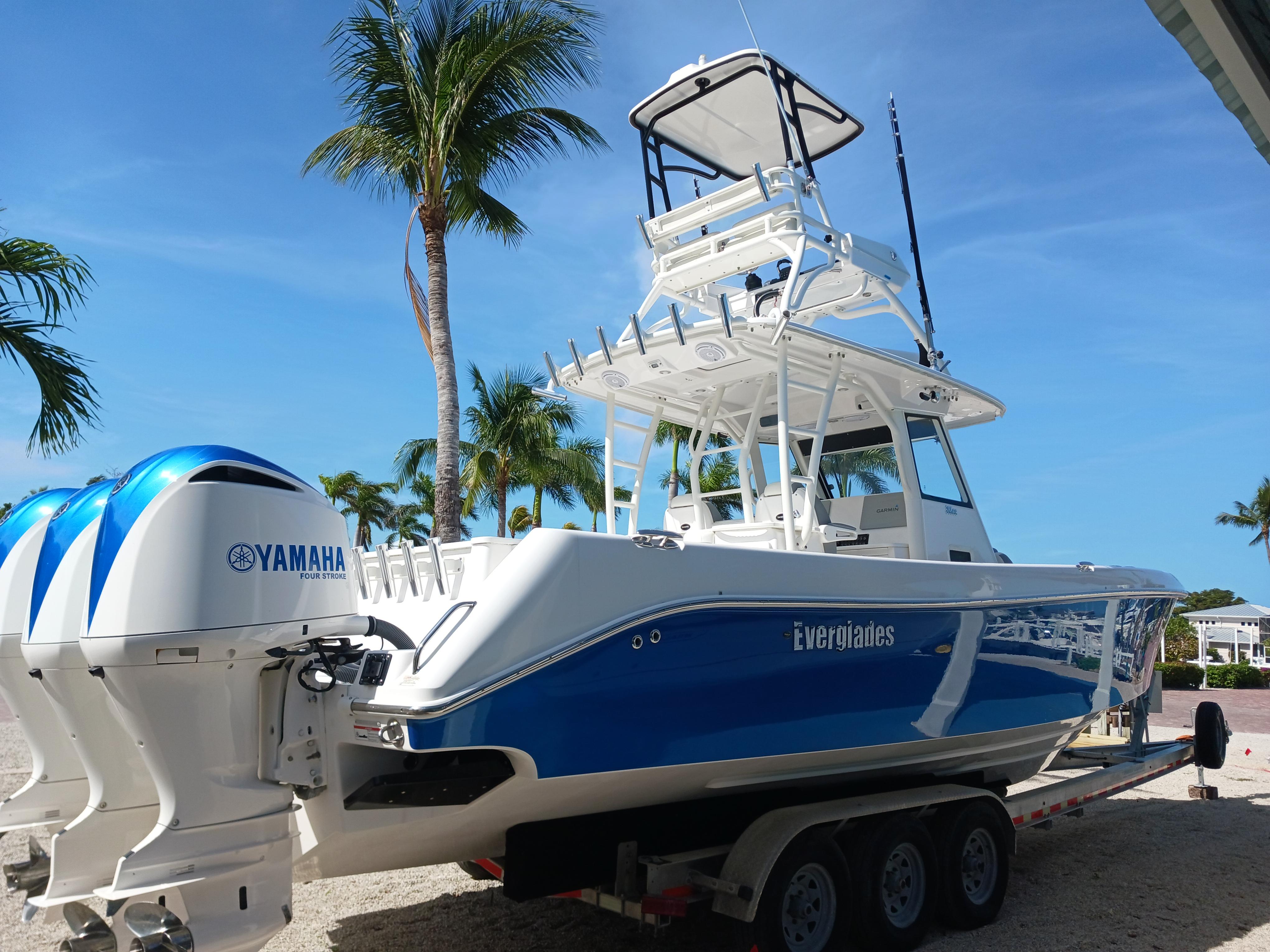 Everglades 355 2017 Everglades 355 boat with Yamaha engines on a trailer, surrounded by palm trees.