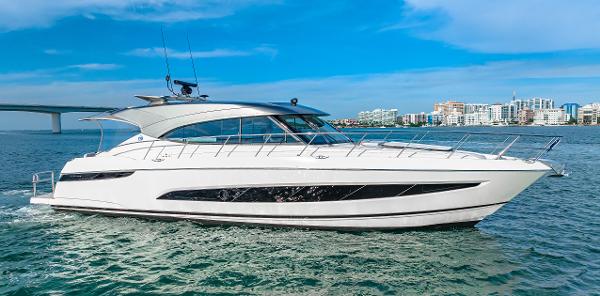 Riviera 5400 Sport Yacht 2025 Riviera 5400 Sport Yacht cruising on open water, cityscape in background.