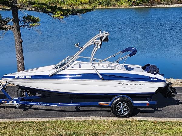 Crownline 195 SS 2012 Crownline 195 SS boat on trailer by a lake, featuring sleek design and blue accents.