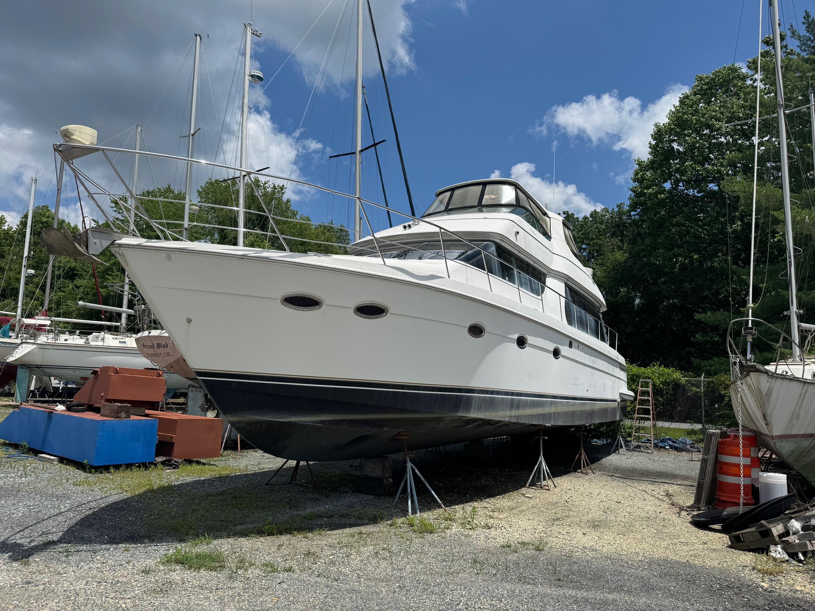 Carver 570 Voyager Pilothouse 2003 Carver 570 Voyager Pilothouse yacht on dry dock, surrounded by trees and other boats.